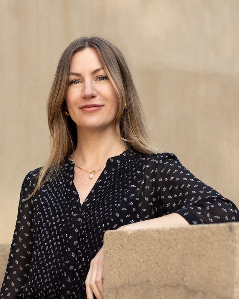 Candace Hamann, LCSW, smiling, standing outdoors against a warm stone wall